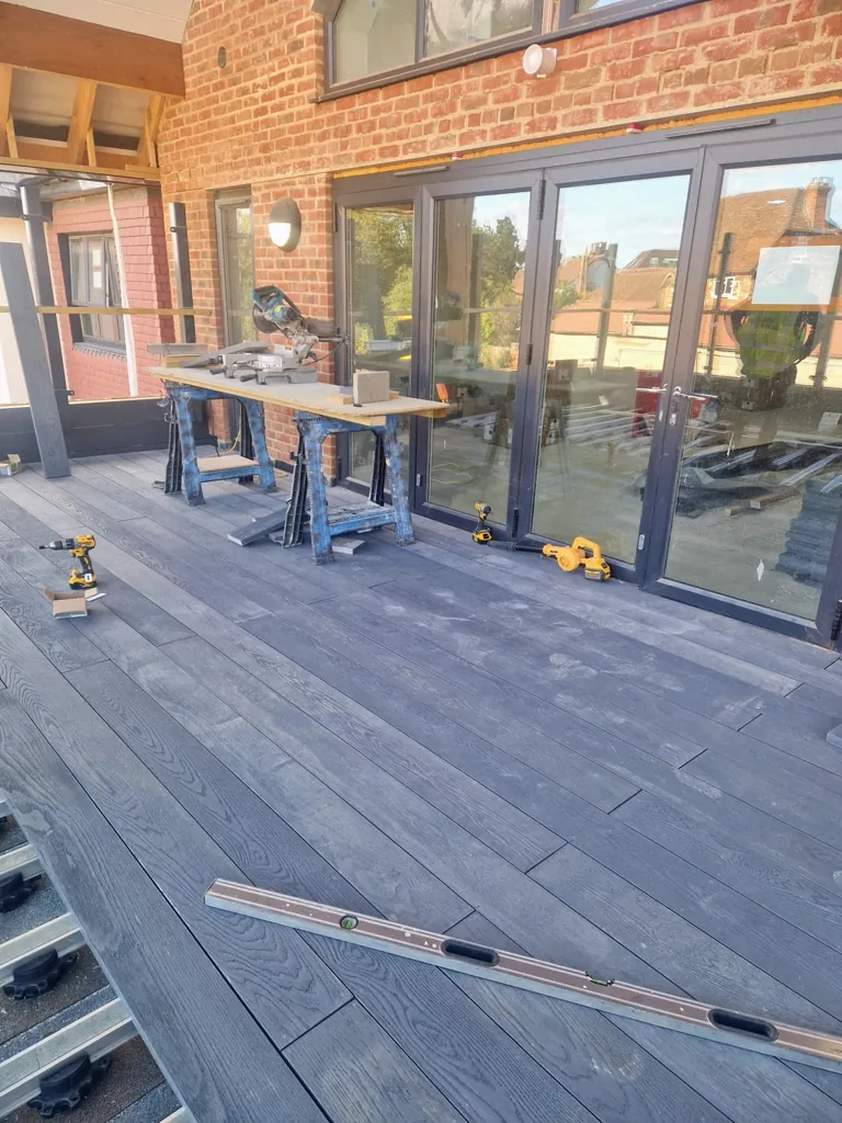 Composite decking installation near building facade with tools and materials laid out