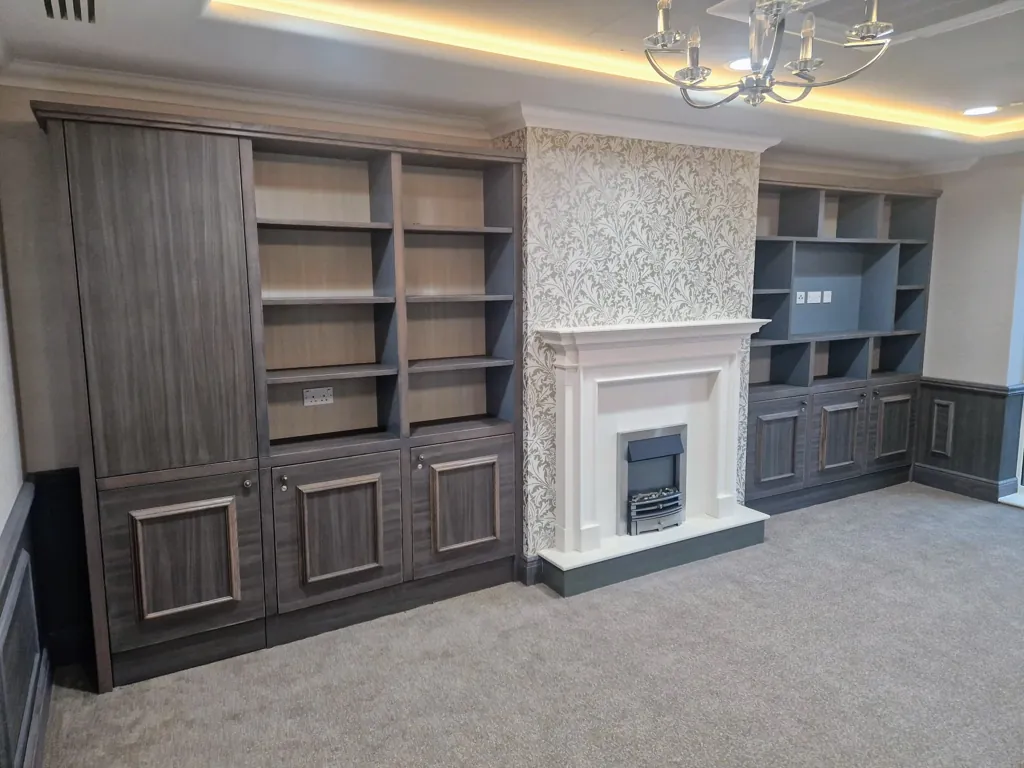 Built-in cabinetry and shelving units around a fireplace with decorative wall finish