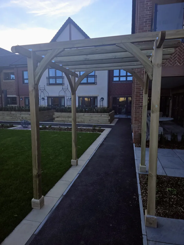 Timber pergola installed over pathway leading through landscaped garden area