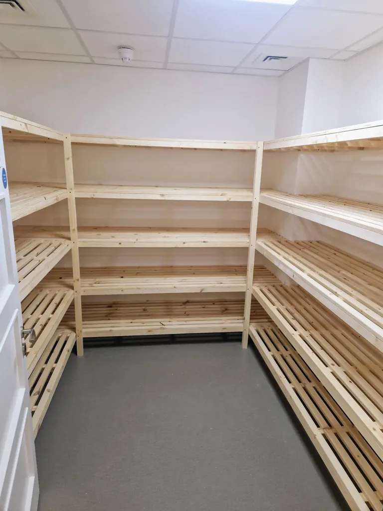 Storage room with wooden batten shelving units installed along multiple walls