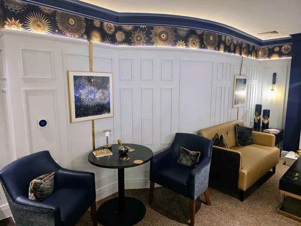 Lounge seating area with armchairs, sofa, round table and decorative wall panelling with artwork