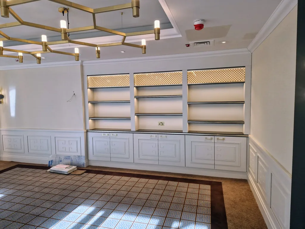 Built-in shelving and cabinetry with decorative lighting in a communal interior space