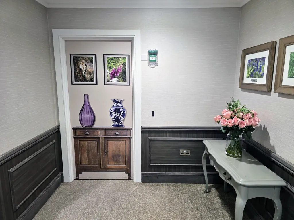 Hallway with wall panelling, console tables and decorative vases and artwork